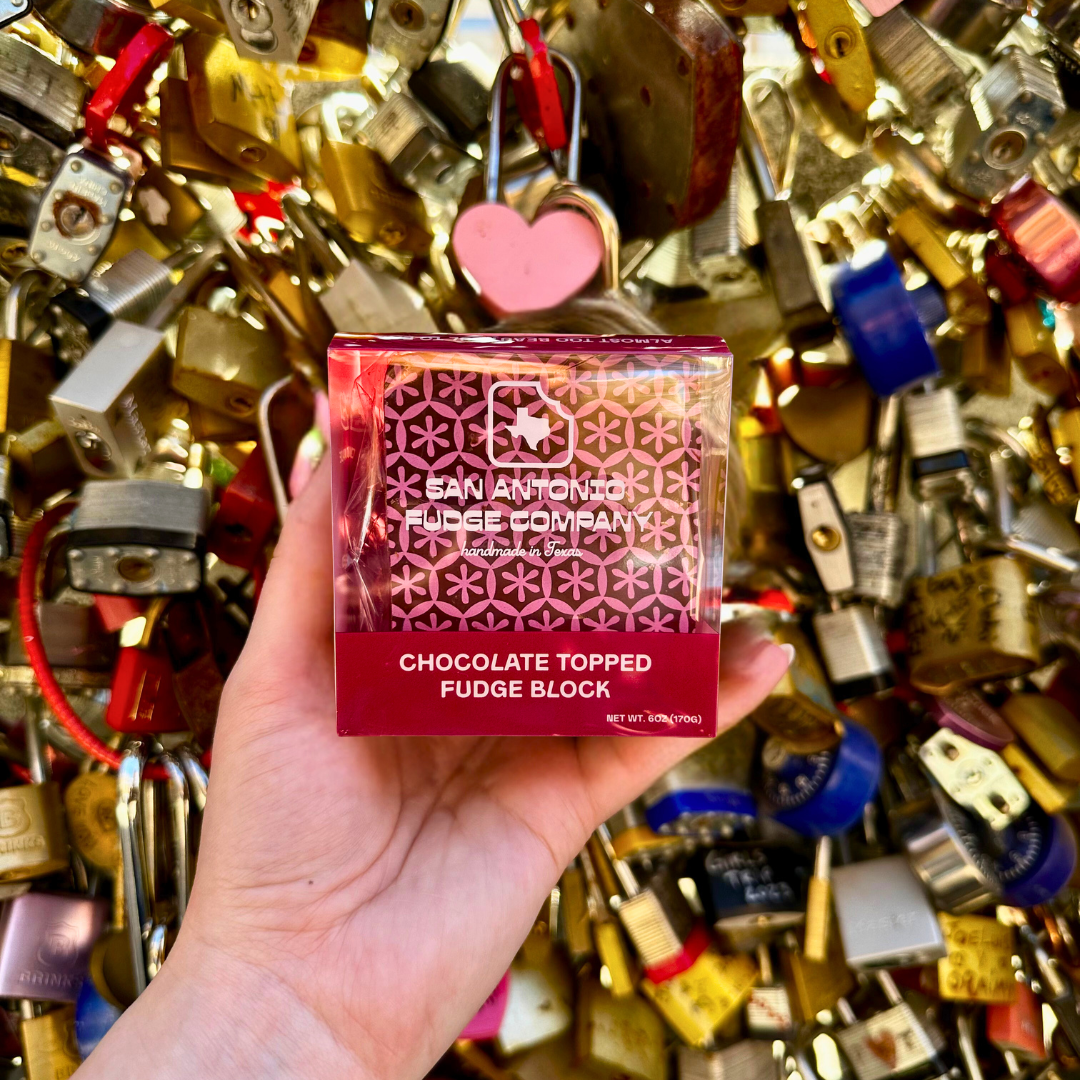 Hand holding a chocolate topped fudge block against a background of padlocks